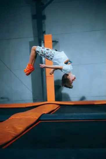 Jeune trampoliniste en salto arrière sur trampoline freestyle